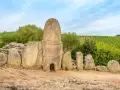 Antiche pietre di un sepolcro a "pozzo" in Sardegna, un vero Stonehenge sardo, circondato da vigneti verdi.
