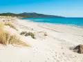 Spiaggia di Porto Pino con dune sabbiose e mare turchese sotto un cielo azzurro.