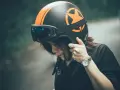 Ragazza con casco moto nero e arancione, occhiali vintage. Guida sicura: come scegliere casco moto.