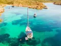Vela al largo di Cala Ambra, con acque cristalline e un paesaggio roccioso.