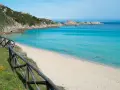 Una splendida spiaggia rena bianca bagnata da un mare cristallino. La vegetazione mediterranea e le rocce scolpite dal vento completano il paesaggio.