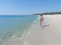 Bambino cammina su una delle splendide spiagge della costa est della Sardegna, con mare cristallino e sabbia bianca.