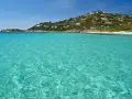 Acque cristalline e una collina verdeggiante punteggiata di case bianche e rosse, con la **spiaggia Torre delle Stelle** che si estende in lontananza.
