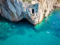 Porto Flavia, un'antica struttura legata alle miniere abbandonate della Sardegna, si affaccia su un mare cristallino. Kayak solcano le acque turchesi.