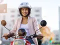 Donna sorridente in motorino, con casco bianco, rispetta l'obbligo casco motorino per la sua sicurezza.