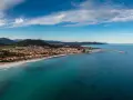 Vista aerea di Posada, Siniscola, con la sua spiaggia dorata, il mare turchese e le case colorate che si affacciano sulla costa.