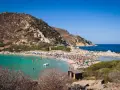 Una giornata di sole a Punta Molentis beach, con acque cristalline, sabbia dorata e tante persone che si godono il mare.