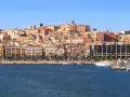 Vista del quartiere Marina di Cagliari con palazzi colorati, palme e yacht ormeggiati.