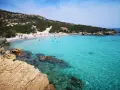 La **cala Granara** splende con acque cristalline e una spiaggia affollata di bagnanti. Rocce dorate emergono dal mare turchese.