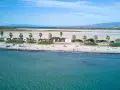 Spiaggia di Putzu Idu con palme, camper e gente che si gode il sole. Acqua cristallina e cielo azzurro.