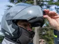 Uomo con casco modulare grigio, pronto per un viaggio in moto. Goditi la strada con questi caschi più silenziosi.