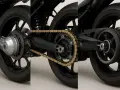 Dettaglio posteriore moto: confronto tra trasmissione a catena dorata e trasmissione a cinghia. Ideale per la sostituzione catena moto.