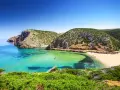 Baia con acque cristalline e sabbia dorata, incastonata tra scogliere verdi. Un vero gioiello tra le spiagge più belle in Sardegna.