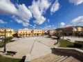 Piazza di San Giovanni Suergiu con edifici gialli e cielo azzurro.