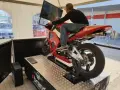 Uomo su una moto rossa da corsa, seduto su un simulatore di guida. Un'esperienza di guida virtuale con un sag moto.