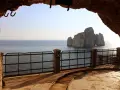 Vista dal **Porto Flavia**, con il mare calmo e il faraglione di Pan di Zucchero che emerge dalle acque.