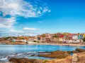 Colorate case affacciate sul mare blu, con rocce in primo piano. Il centro storico di Porto Torres, un incanto sardo.