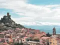 Borgo medievale di Burgos, Sardegna, con castello in rovina su uno sperone roccioso e case colorate a valle.