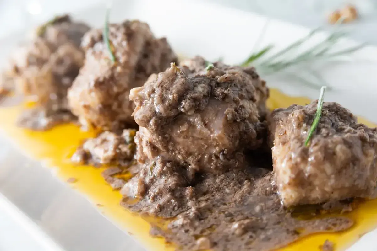 Burrida cagliaritana: bocconcini di pesce in salsa scura e dorata, guarniti con rosmarino.