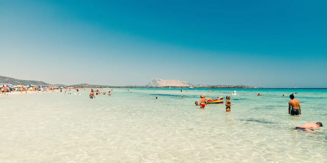 Splendida giornata al mare della Sardegna, con acque cristalline e gente che si gode il sole e il mare.