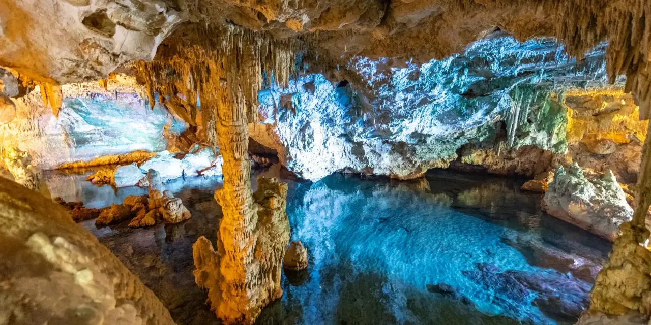 Stalattiti e stalagmiti illuminano le **grotte di Ispinigoli**, con un lago sotterraneo dalle acque cristalline e turchesi.