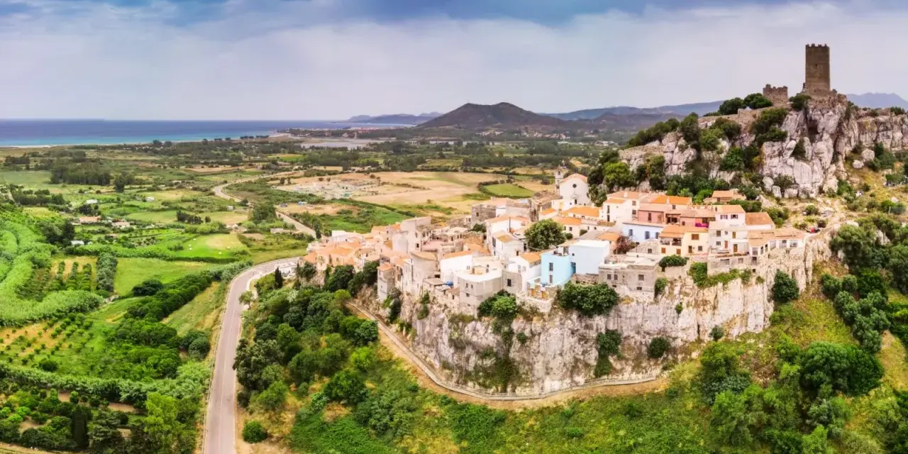 Borgo arroccato su una rupe con un castello medievale, affacciato su un paesaggio verdeggiante e il mare. La **posada dove si trova** è un gioiello incastonato nella roccia.