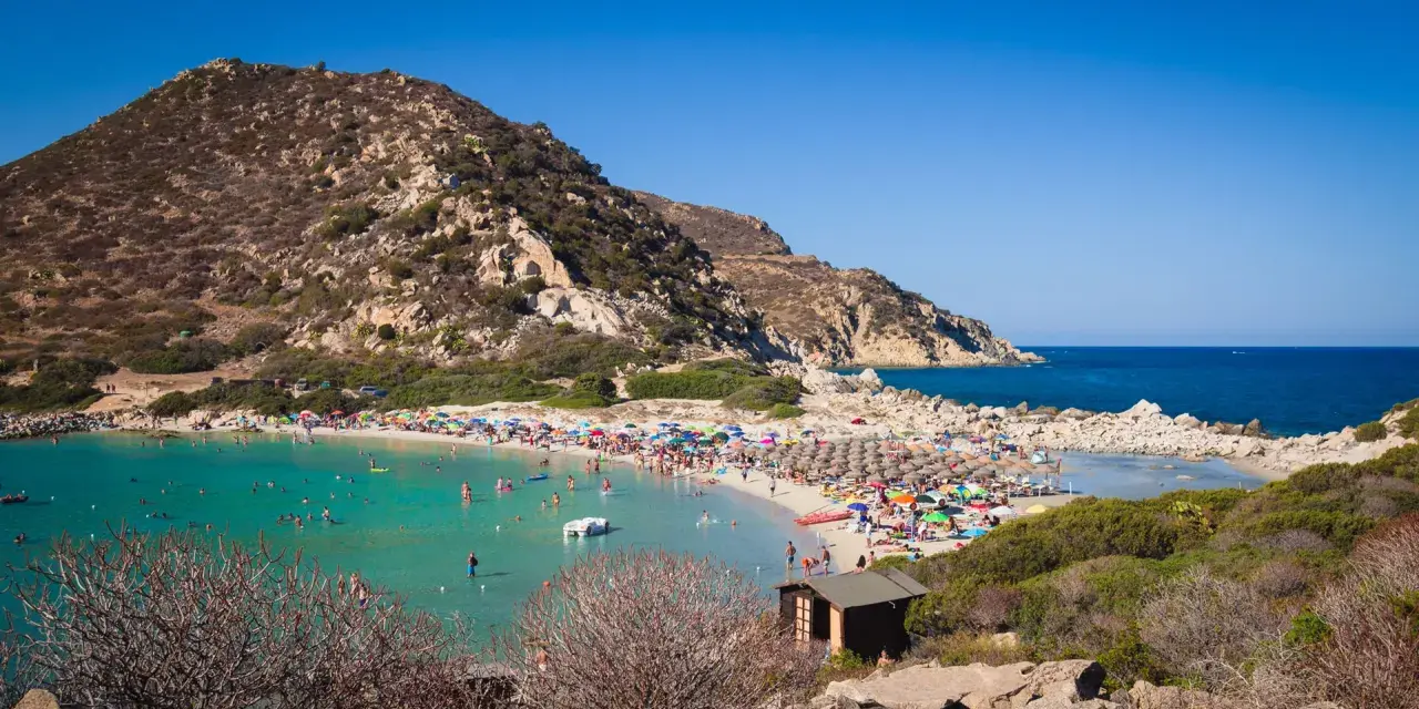 Una giornata di sole a Punta Molentis beach, con acque cristalline, sabbia dorata e tante persone che si godono il mare.