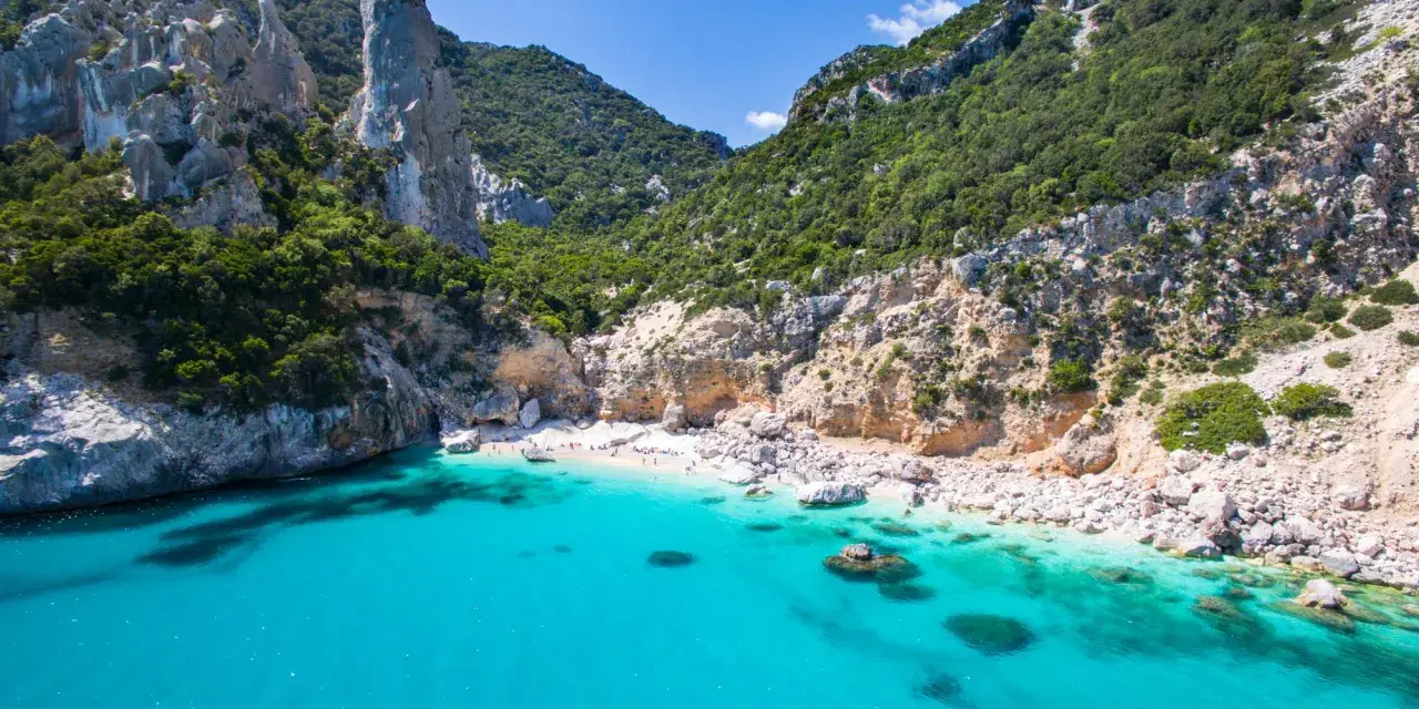 Spiaggia rosa di Budoni, incastonata tra scogliere imponenti e un mare cristallino.