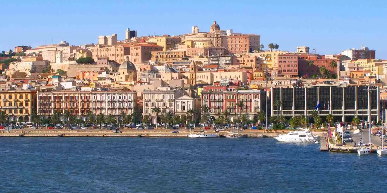 Vista del quartiere Marina di Cagliari con palazzi colorati, palme e yacht ormeggiati.