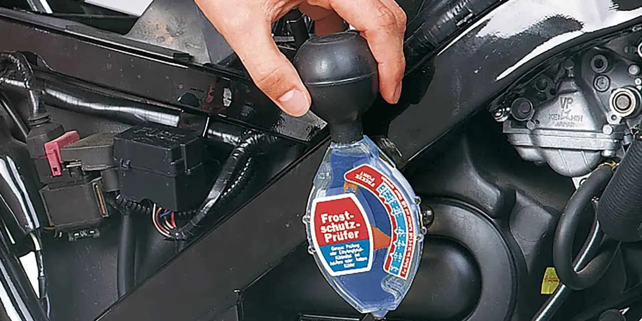 Controllo del liquido di raffreddamento a liquido moto con un densimetro. La mano tiene lo strumento per verificare la protezione antigelo.