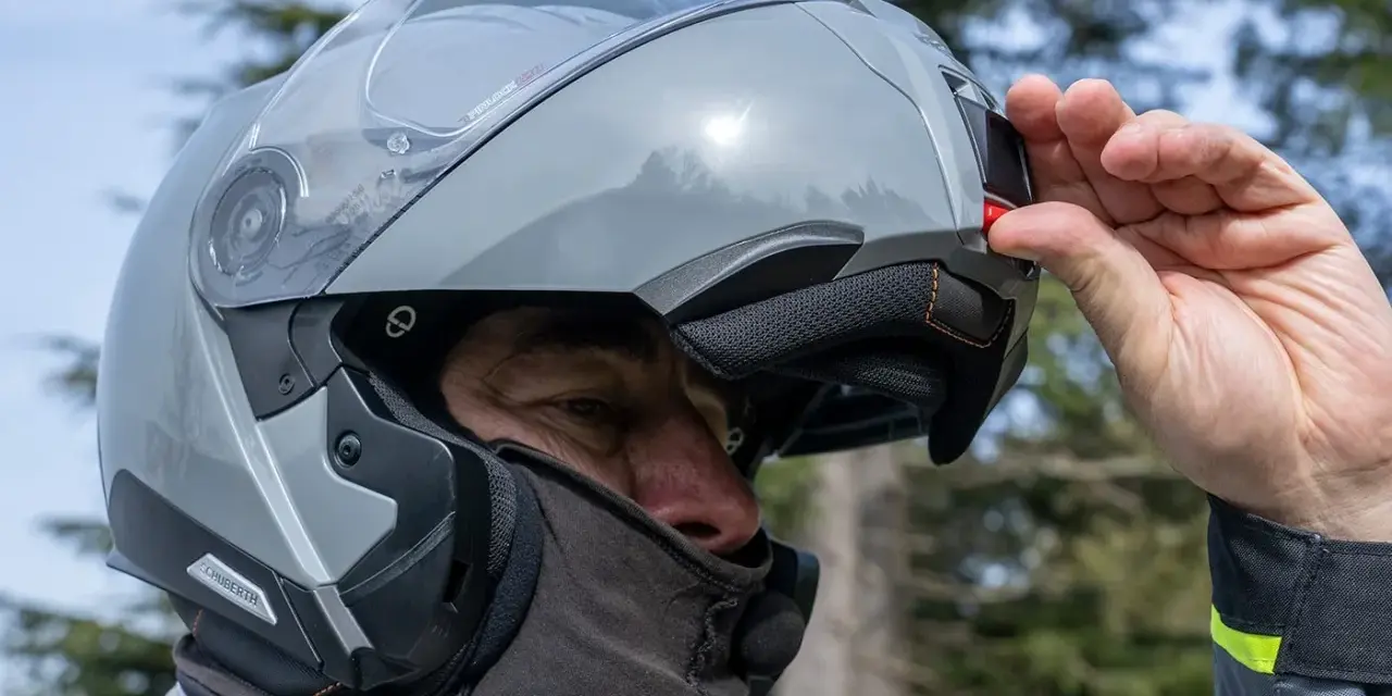 Uomo con casco modulare grigio, pronto per un viaggio in moto. Goditi la strada con questi caschi più silenziosi.