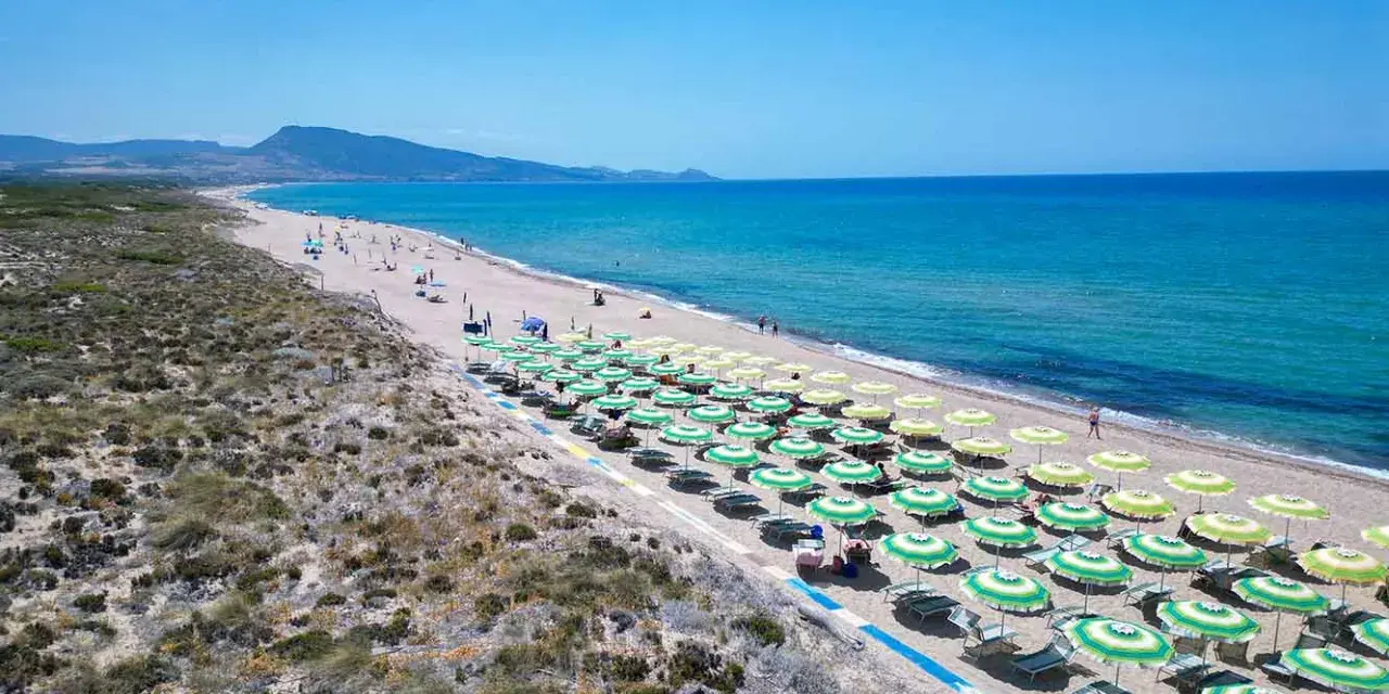 Spiaggia di Badesi: file di ombrelloni verdi e gialli, mare azzurro e dune sabbiose. Cosa vedere in questo paradiso.