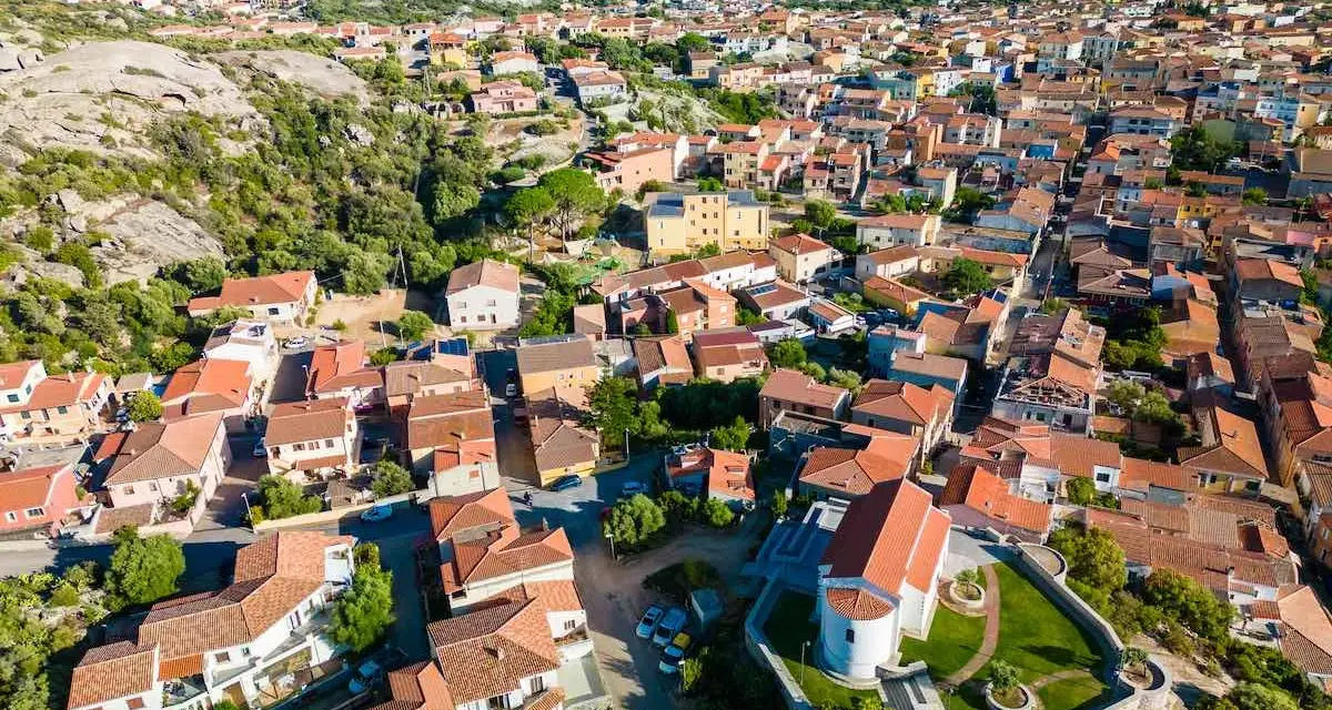 Vista aerea del centro storico di Arzachena, con le sue case dai tetti rossi e la chiesa in primo piano.