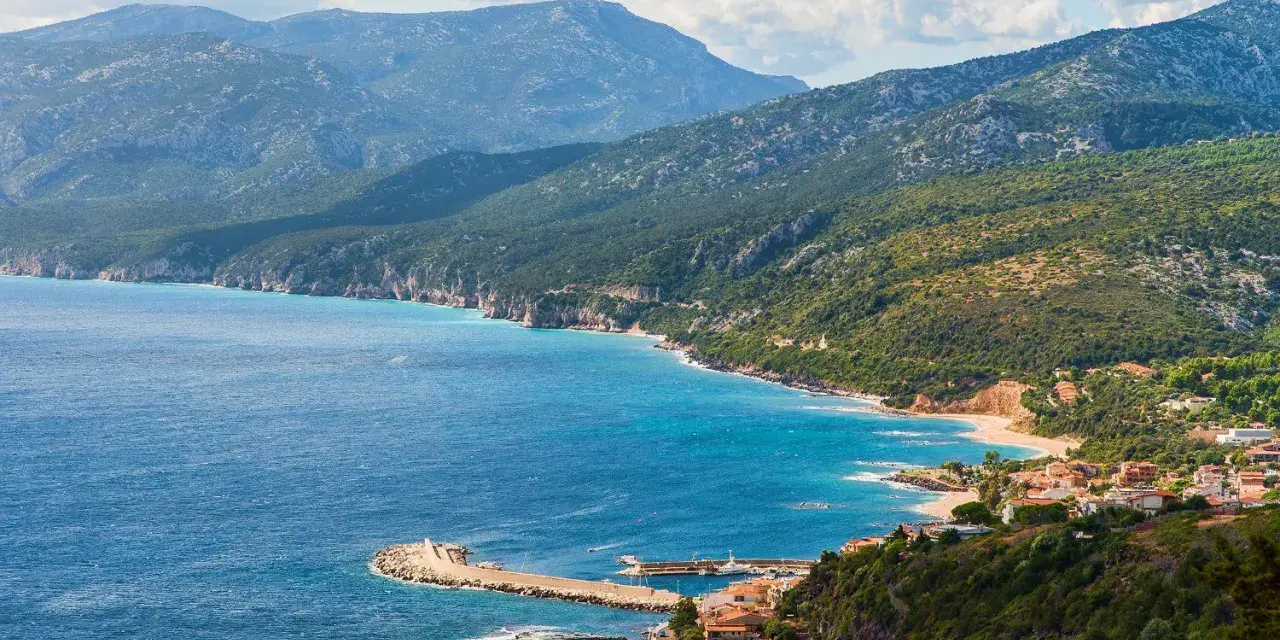 Vista panoramica di Cala Gonone, dove il blu intenso del mare incontra la costa frastagliata e le verdi montagne.