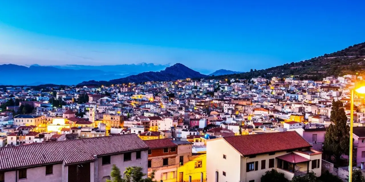 Vista serale di Cala Gonone, con luci accese tra le case. Perfetto per scoprire cosa fare la sera.