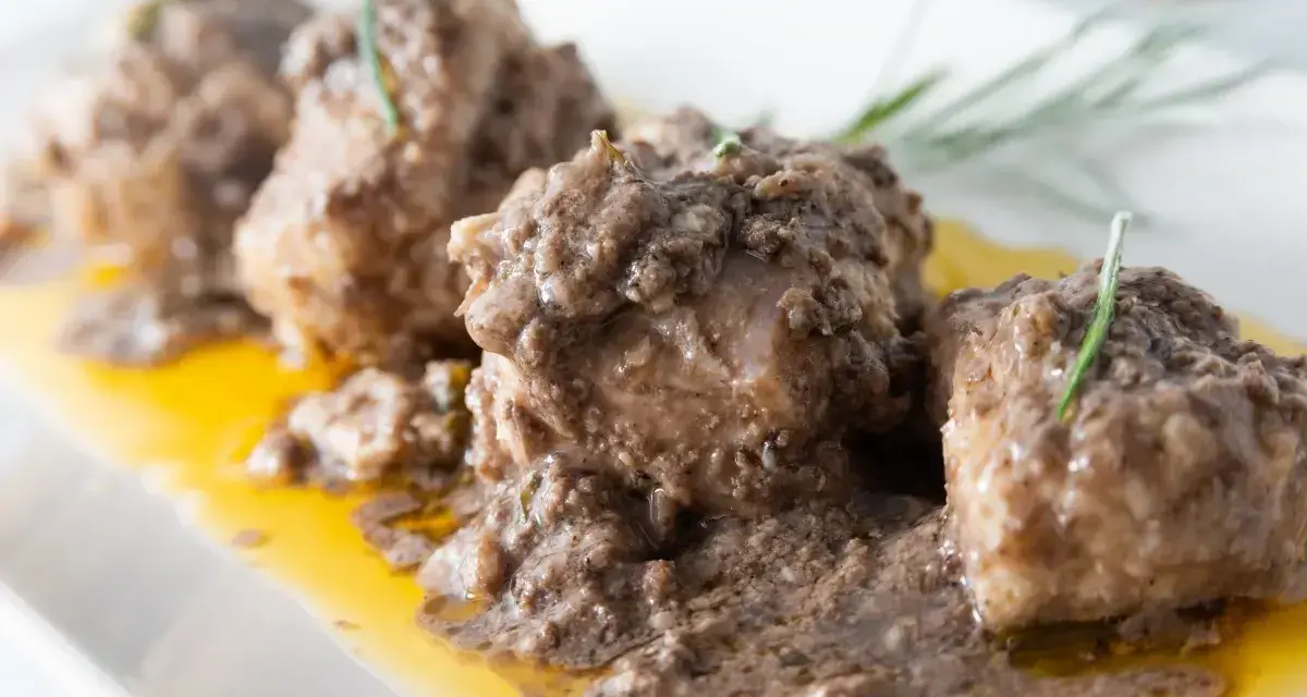Burrida cagliaritana: bocconcini di pesce in salsa scura e dorata, guarniti con rosmarino.