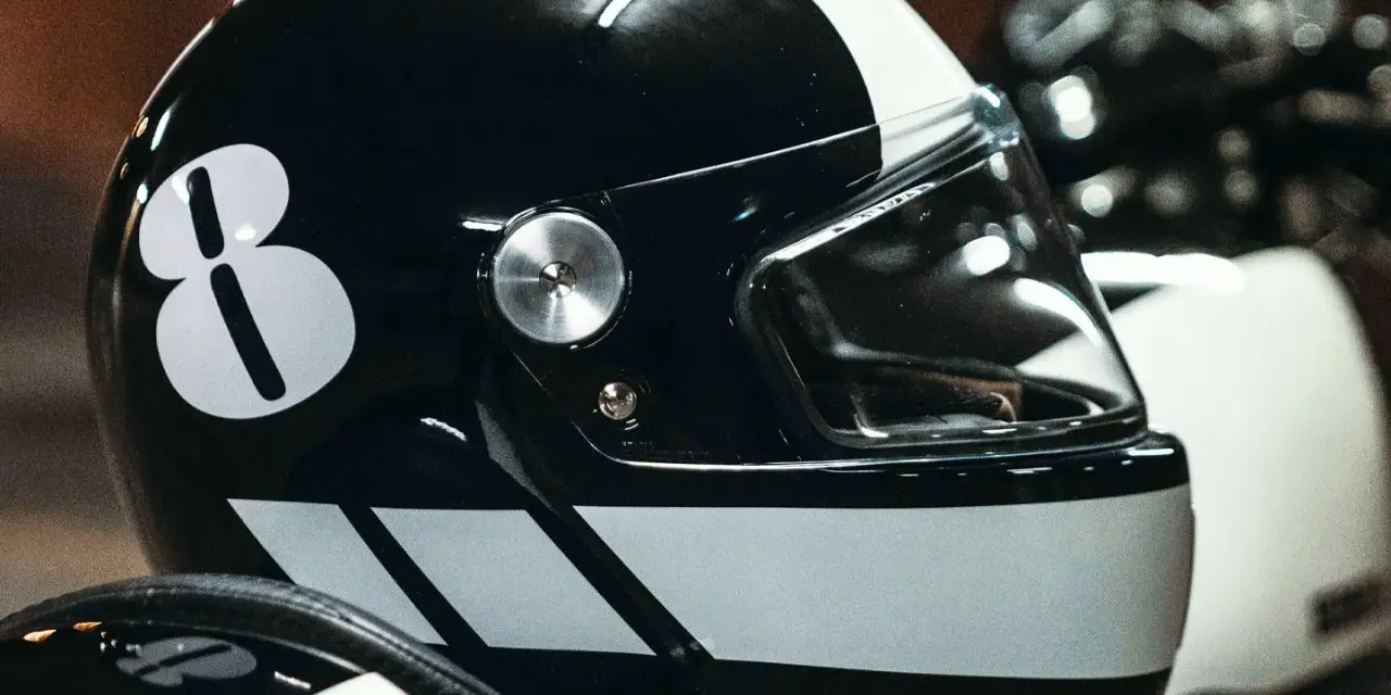 Casco nero con numero 8 bianco e strisce. Per sapere come non far appannare la visiera del casco, guarda questo dettaglio.