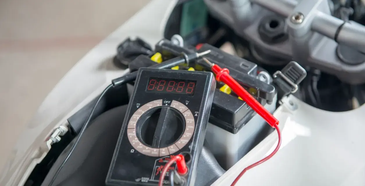Multimetro collegato alla batteria della moto per verificarne lo stato prima di staccare la batteria moto inverno.