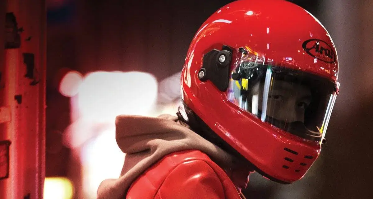 Un motociclista indossa un casco integrale rosso brillante, pronto per la strada.