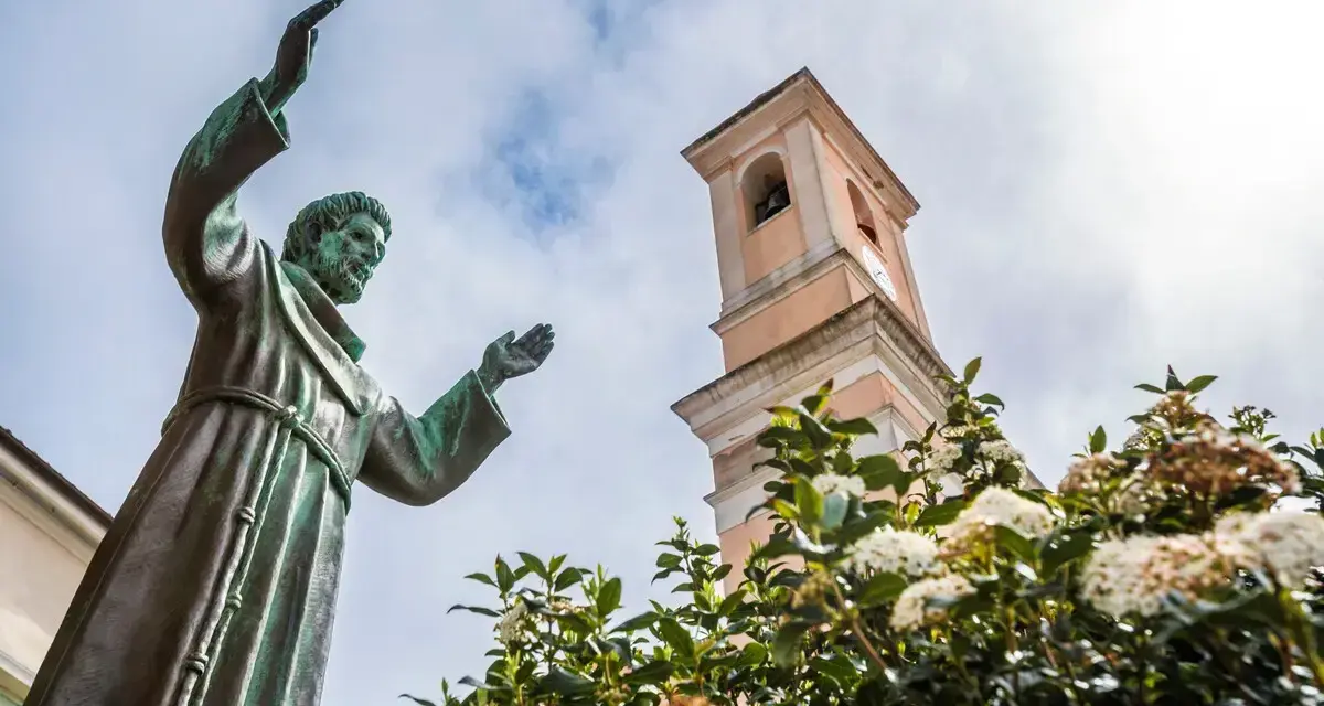 Statua di San Francesco con campanile e fiori. Il **Nuoro significato** di questo luogo è legato alla spiritualità e alla natura.