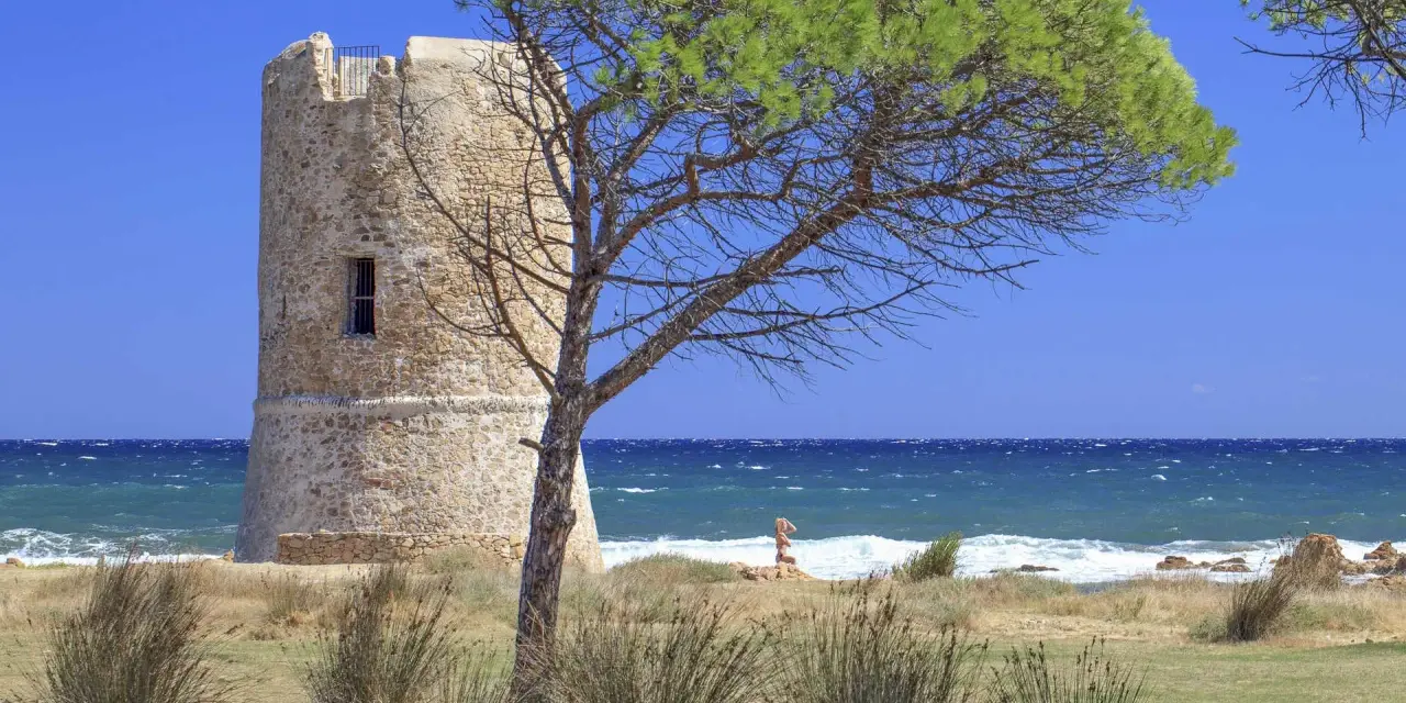Torre aragonese a San Giovanni di Posada, con pini marittimi e mare in tempesta.