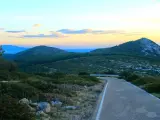 Strada panoramica verso il monte Doglia al tramonto, con colline verdi e cielo colorato.