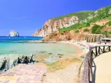 Spiaggia di Masua con acque cristalline, scogliere imponenti e il Pan di Zucchero all'orizzonte. Relax e natura incontaminata.