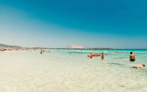 Splendida giornata al mare della Sardegna, con acque cristalline e gente che si gode il sole e il mare.