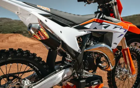 Scarico FMF su KTM arancione e bianca. La moto da cross, con il suo motore 2t, è pronta per la pista.