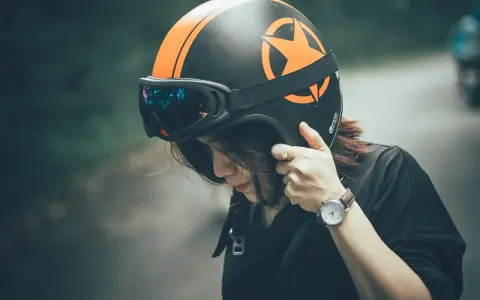 Ragazza con casco moto nero e arancione, occhiali vintage. Guida sicura: come scegliere casco moto.