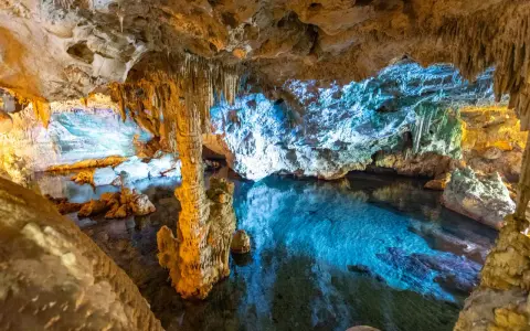 Stalattiti e stalagmiti illuminano le **grotte di Ispinigoli**, con un lago sotterraneo dalle acque cristalline e turchesi.
