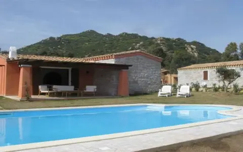Una villa con piscina azzurra e montagne verdi sullo sfondo. Perfetta per una vacanza di relax, sa sippa.