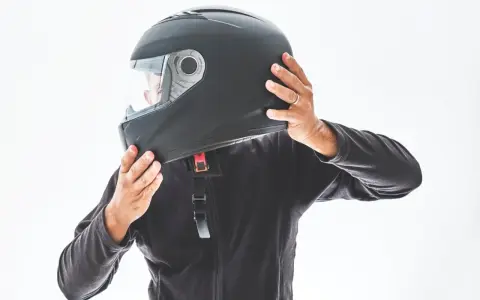 Persona indossa un casco integrale nero, pronto per un'avventura in moto.