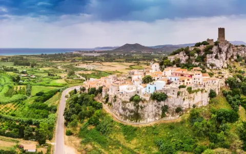 Borgo arroccato su una rupe con un castello medievale, affacciato su un paesaggio verdeggiante e il mare. La **posada dove si trova** è un gioiello incastonato nella roccia.